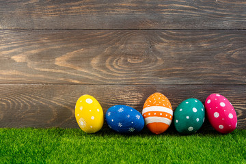 Happy Easter background. Easter eggs on the grass with wooden background. Festive decoration. Copy space