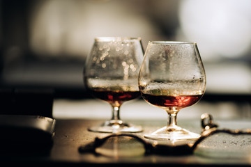  Two glasses of cognac on wooden table in dark light
