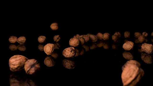 Vegan-Approved Organic Walnuts Falling onto Glassy Black Surface