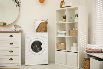 Modern washing machine near white wall in elegant bathroom
