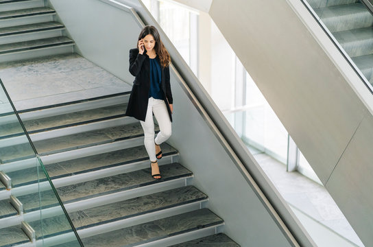 Businesswoman walking down stairs talking on the phone