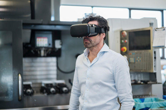 Businessman wearing VR glasses in a factory