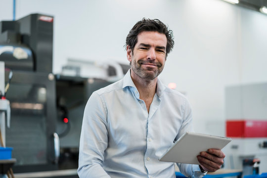 Portrait of a confident businessman holding tablet in a factory