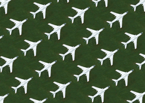 Aerial view of rows of airplanes standing on green grass