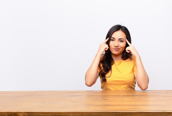 young latin pretty woman looking concentrated and thinking hard on an idea, imagining a solution to...