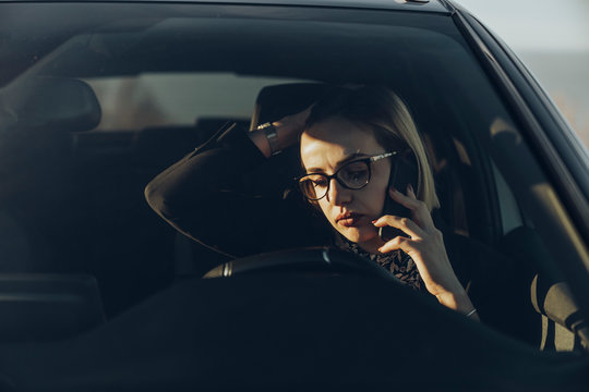 Young blond businesswoman using smartphone in the car