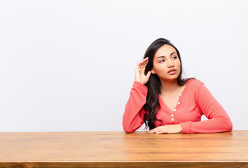 young latin pretty woman looking serious and curious, listening, trying to hear a secret...