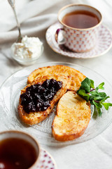Delicious sunday breakfast. Toasts with jam, cream cheese, tea. Soft morning light, close up. Cozy atmosphere of early morning at home. Family time.