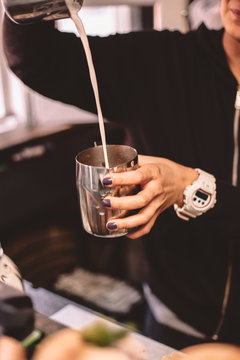 Cropped image of female barista pouring milk from jug to jug