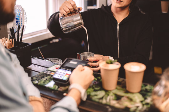 Customer talking with female barista while buying coffee at cafe