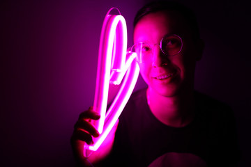 Valentine day. Hipster handsome man with neon signs. Neon sign pink heart. Party concept. Modern style. Neon sign. 