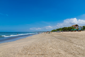 Fototapeta na wymiar KUTA, BALI / INDONESIA - NOVEMBER 8, 2019: Kuta beach in Bali. Wide sandy beach with many sunbeds and umbrellas. Best place for surfing.