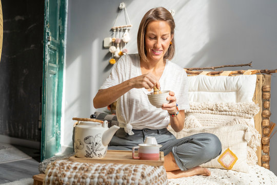 Girl preparing matcha tea in a traditional way on the sofa