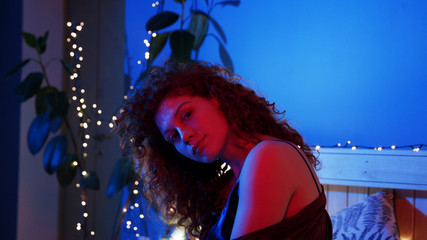 Portrait young attractive woman showing herself in sexual poses on bed in sleepwear at night colorful light lying apartment bed female room night sensual exciting sexy close up slow motion © Fractal Pictures