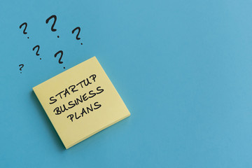 Business concept - Startup business plans text on sticky notes with question marks