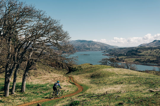 A young woman bikes along a trail overlooking the Columbia River.
