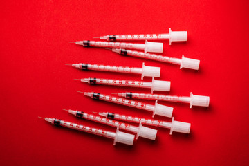 Pile of medical syringes for insulin for diabetes. Syringe on red background 