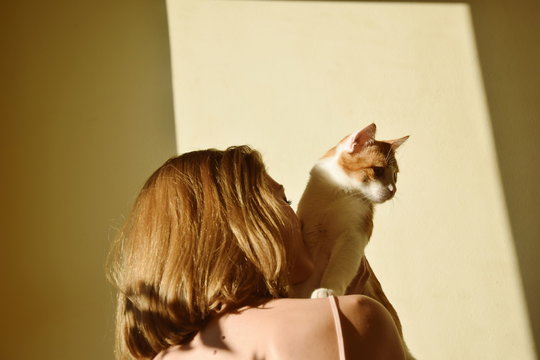 Low Angle View Of Woman With Cat Against Wall