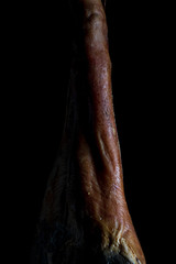 The art of Spanish Iberian ham. Whole leg with artistic look on a black background.