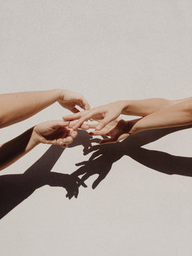 Cropped Hands Of People Against Gray Wall