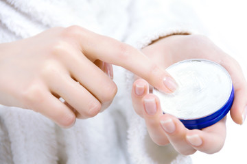 Closeup of female hands are holding blue box, bottle. Young woman is going to smear apply her body with moisturizing, nutritious cream after shower, bath. Personal hygiene and care product concept.