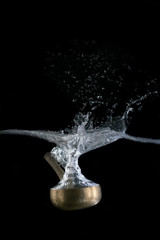  Singing bowl, Tibetan, plunging into water. On black background.