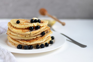 A stack of delicious pancakes with raspberries, blackberries and blueberries. On a light background. Sprinkled with icing sugar and decorated