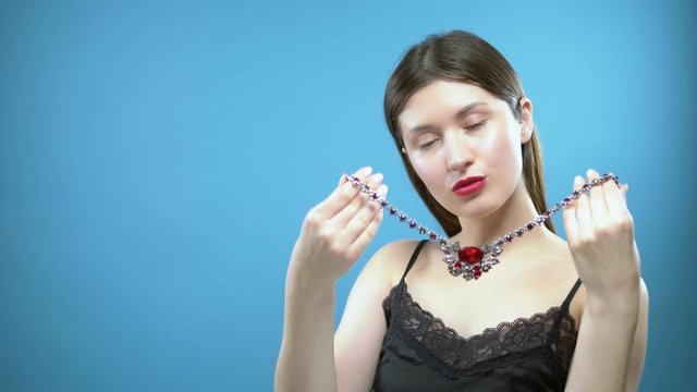 beautiful young girl wears a necklace. blue background