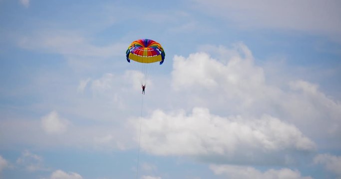 parasailor flying in the sky with parachute  parasaling parachute moving in the sky tourist parasaling in sunny day