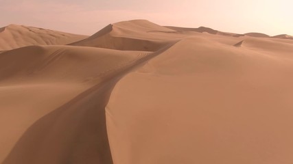 Sandy desert oasis lake. DRONE. Water in middle of hot sand desert. Romantic, holiday, couple, honeymoon, scenic shot, with sand and footprints. Tourism shot in Huacachina, Peru. Epic, dramatic shot. - Powered by Adobe