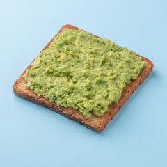 Toast with mashed avocado on blue background
