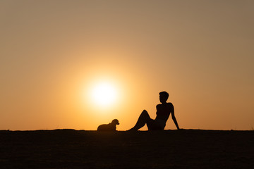 a silhouette of a woman is sitting on the beach