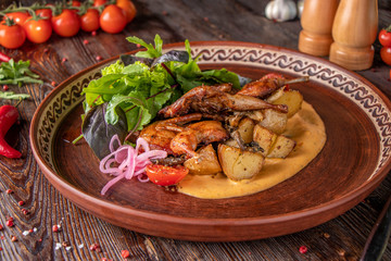 Baked quails with potatoes served with saffron sauce and green salad, a restaurant dish, Close up