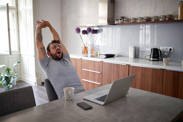 Sleepy guy yawns and stretching at the morning.