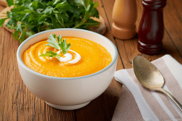 Pumpkin soup with milk cream and parsley in a bowl