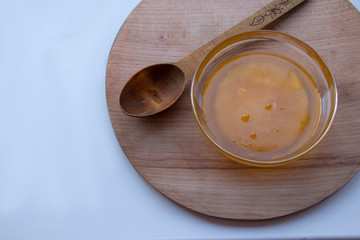 Sweet yellow honey in a glass bowl on a wooden board with a large wooden spoon. Sweet.