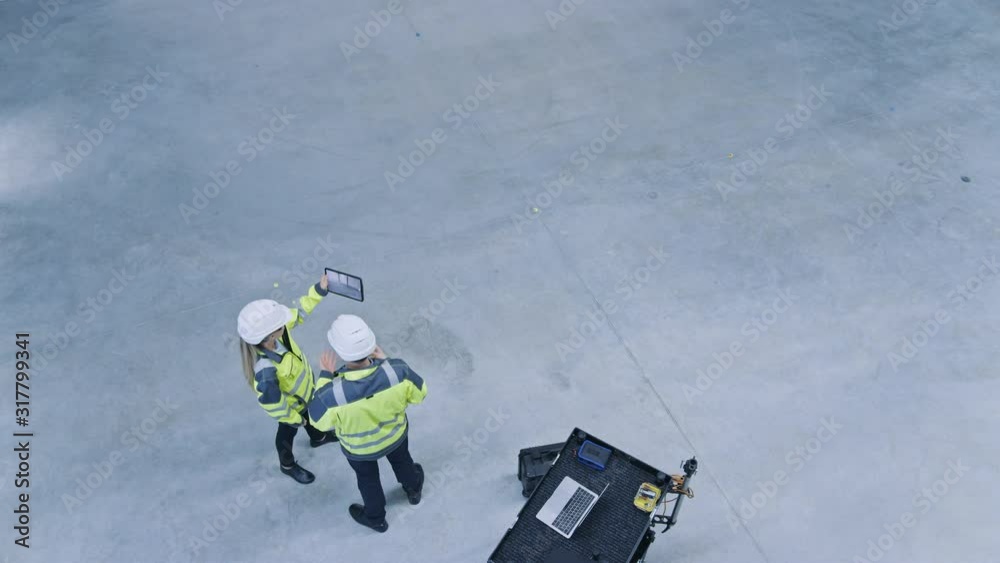 Aufkleber Industry 4.0 Modern Factory: Two Engineers Use Digital Tablet Computer with Augmented Reality Software Visualizing of Manufacturing Plant Room Mapping. Doing 3D Factory Floor Layout. High Angle Shot