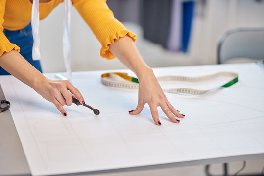 Dedicated caucasian seamstress cutting seam pattern with rotary cutter.