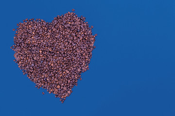 Classic blue background. A heart made of coffee beans is a symbol of love.  Space for text. Color 2020. Layout. Top view, empty space.