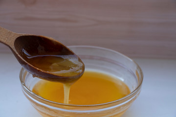 Yellow sweet honey on a white background. Flowing sweetness with a wooden spoon. Bee.