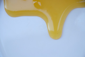 Yellow sweet honey on a white background. Flowing sweetness with a wooden spoon. Bee.
