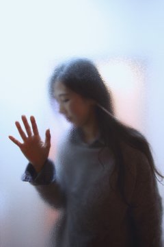 Young woman seen through glass window