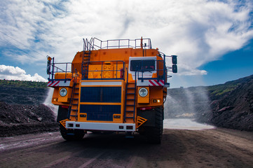 Heavy truck pours the road with water in the iron ore quarry. Dust removal, protection of the environment. Irrigation of the road from dust. The World’s Largest Sprinkler Truck