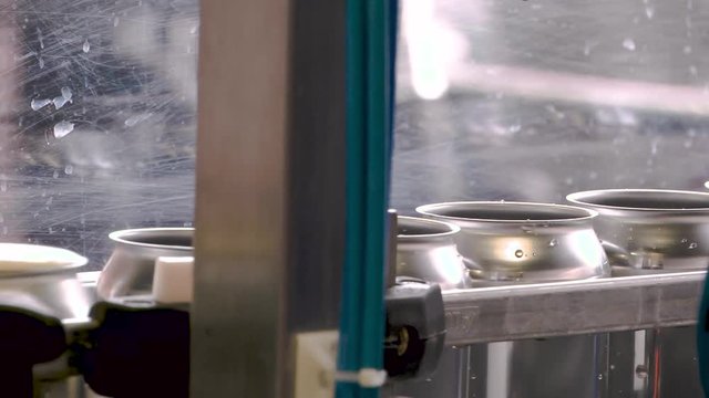 Empty beer cans being filled up with beer on a canning line at a brewery. Close Up.