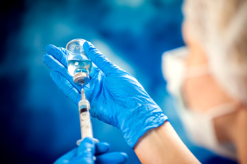A doctor holding a bottle with vaccine and syringe. Medicine and healthcare concept