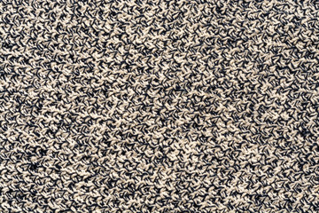 A close-up of knitted things made of black and white threads. Original background
