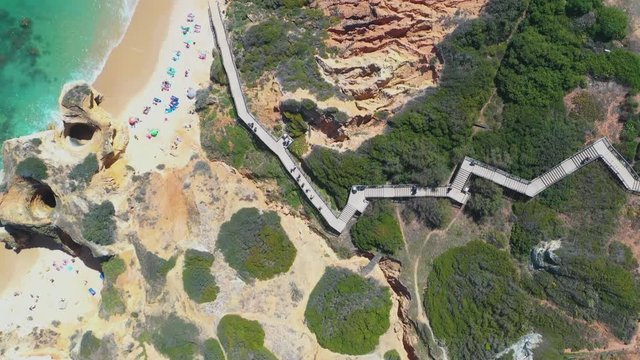 Flying Above Cliff With Andy Beach Along Stairs And Car Parking Area. Aerial View. Praia do Camilo, Algarve, Lagos, Portugal