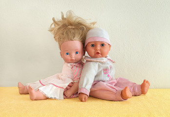 Tiny tots dolls in pink clothes. Nursery dolls sitting back to back on yellow underlay next to the...