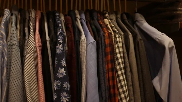 Large assortment of shirts displayed on clothing rack in men clothes shop  