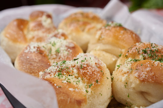 Garlic knots with Parmesan cheese and dried greens on top in a basket